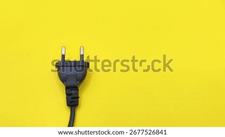top view of black electrical plug isolated on yellow background. rules of thirds composition