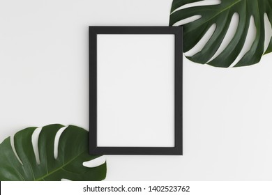 Top View Of A Black Frame Mockup With Monstera Leaf Decoration. Portrait Orientation.