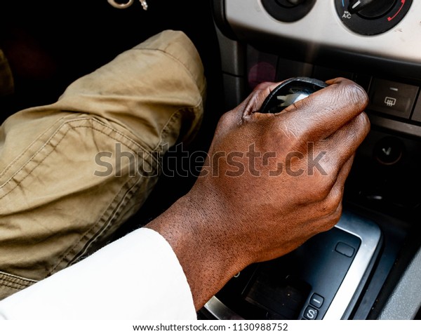 
Top view of Black male
driver hand on manual gear shift knob or Business man driver hand
shifting the gear stick. African American Driver's hand changing
speed