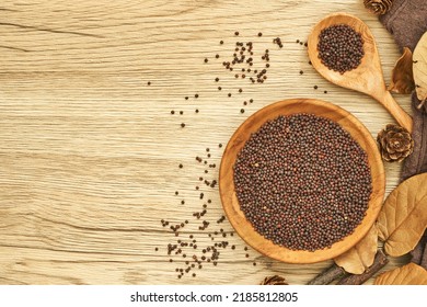 top view black mustard seed in wood plate and spoon on wooden table background. flat lay a pile of black mustard seed in wood plate on wooden table background. overhead
