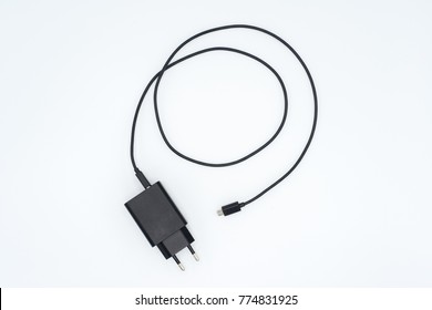 Top View Of Black Phone AC Charger And USB Cable On White Background.