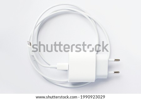 Top view of black phone AC charger and USB cable on white background.
