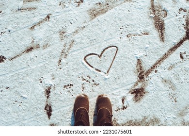Top view black shoes boots footprint in fresh snow  Winter season  Looking at the drawn heart in the snow  Valentines day 