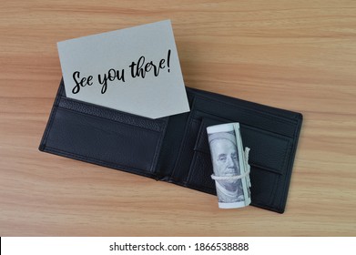Top view of black wallet, money banknotes and grey card written with text SEE YOU THERE. Business concept. 