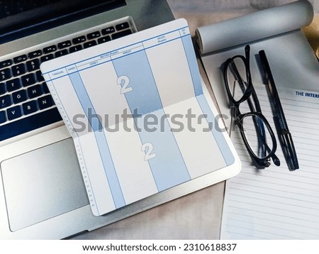 Top view of blank bank saving account book, placed on a laptop, with notebooks and glasses.