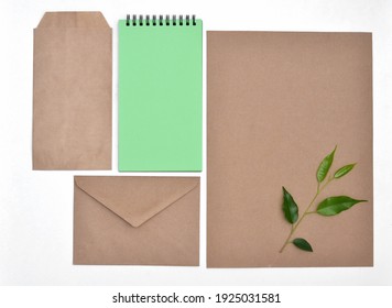 Top View Of Blank Kraft Paper Sheet With Green Branch, Notebook And KRAFT Envelopes. Copy Space. Office Eco Friendly, Home Office Desktop Organisation, Work From Home. 