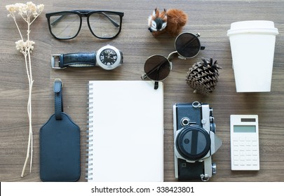Top view of blank note book ,coffee cup ,eyeglasses,camera,watch and calculator on work desk Travel plan concept