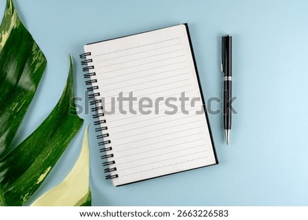 Top view of blank notepad and pen on blue background