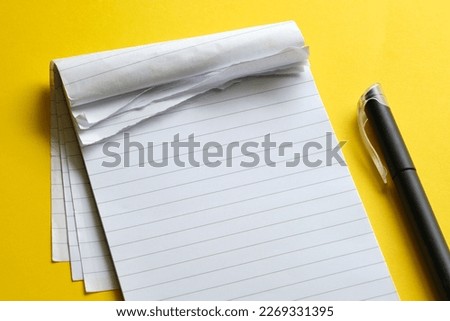 Top view of blank open notebook with torn pages. Page with lines and black minimalistic fineliner pen on yellow background with copy space. For use as mock up or template.       