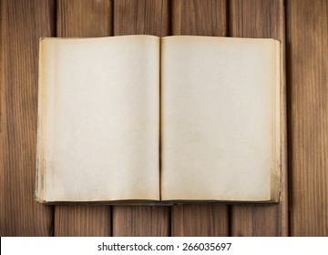 Top view of blank open old book with grange pages on wooden table
