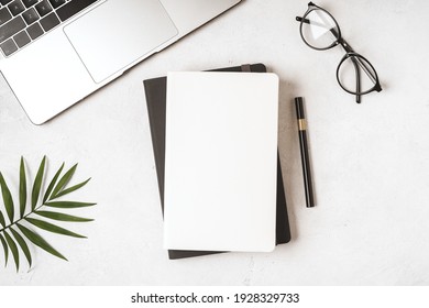 Top view blank paper Notebook, leaf, laptop keyboard, cup of coffee, glasses and pen. Desktop mock up, Flat lay of white working table background with office equipment, mockup. - Shutterstock ID 1928329733