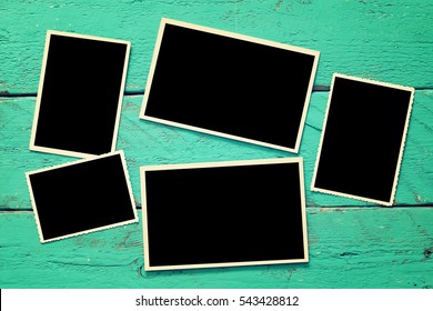 top view of blank photo frames on wooden background.