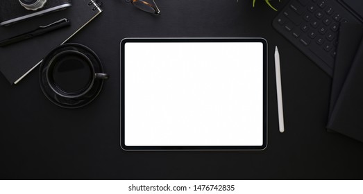 Top View Of Blank Screen Tablet On Black Desk Background In Dark Stylish Workplace And Cup Of Coffee 