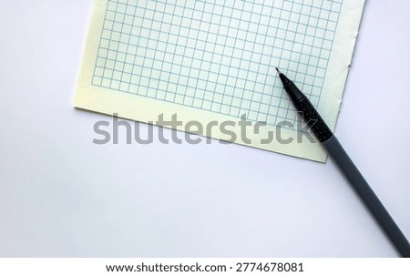A top view of a blank sheet of grid paper with a pen. Isolated on a white background. Space for text.