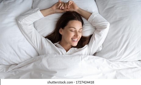 Top View Blissful 30s Woman In White Comfy Nightclothes Lying In Bed At Home Or Hotel Bedroom Enjoy Free Day Holidays, Single Female Wake Up Feeling Rested After Healthy Enough Night Sleeping Concept