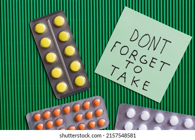 Top View Of Blister Packs With Pills Near Paper Note With Dont Forget To Take Lettering On Textured Green Background