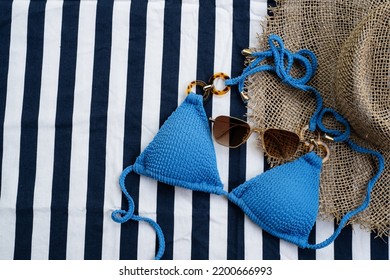 Top View Of Blue Bikini, Sunglasses  And Panama Hat On The Beach Blanket For Picnic On The Beach. Summer Vacation, Summer In Holiday Concept.