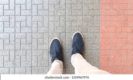 Top View Of Blue Casual Shoes With Beige Pants Standing On A Street Tile.