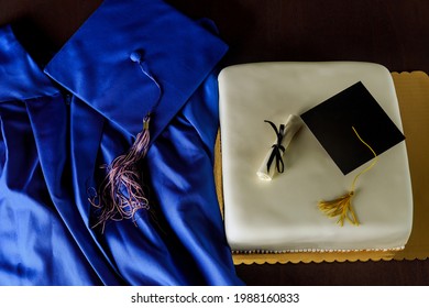 Top View Of Blue Graduation Gown And Cap With Cake For End Of School.