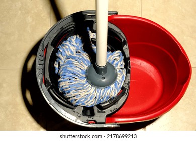 Top View Of Blue Mop Draining In Red Bucket.