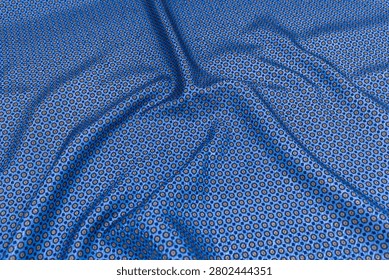 Top view of blue patterned necktie fabric with decorative geometric and floral motifs. Detailed textile texture with elegant folds, suitable as a fashion or luxury background.