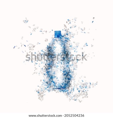 Top view of blue plastic bottle with PET bottle  transparent flakes around in white background. Plastic pollution recycle and World Environment Day concept.