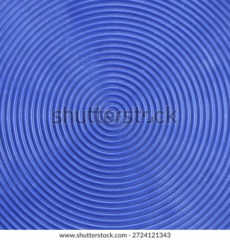 Top view of blue plastic surface with concentric circular ribbed pattern texture.