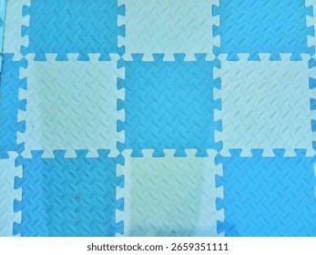 Top view of blue and white interlocking EVA foam puzzle mats, checkerboard pattern floor texture for kids playroom or gym.