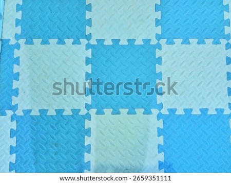 Top view of blue and white interlocking foam floor mats arranged in a checkerboard pattern.