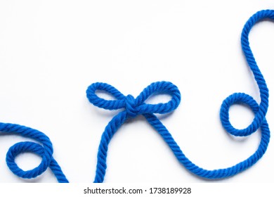 Top View Of Blue Wool Thread And Bow On White Background