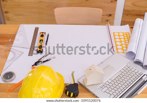 Top view Blueprints,\
helmet, laptop, pencil, dividers, smartphone and engineer equipment\
on working desk.