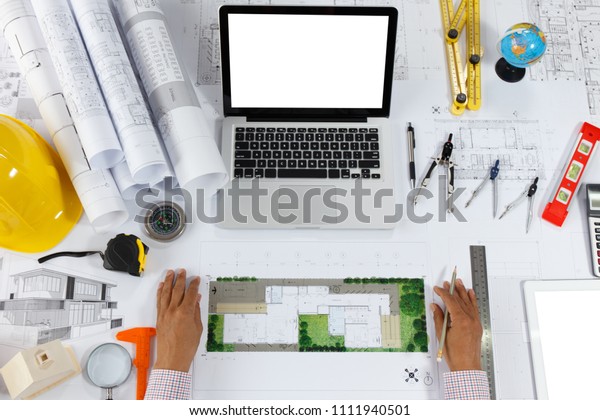 Top view of
Blueprints, helmet, laptop, pencil, dividers, smartphone and
engineer equipment on working
desk.
