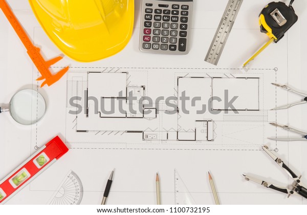 Top view of Blueprints, helmet, pencil,\
dividers and engineer equipment on working\
desk.