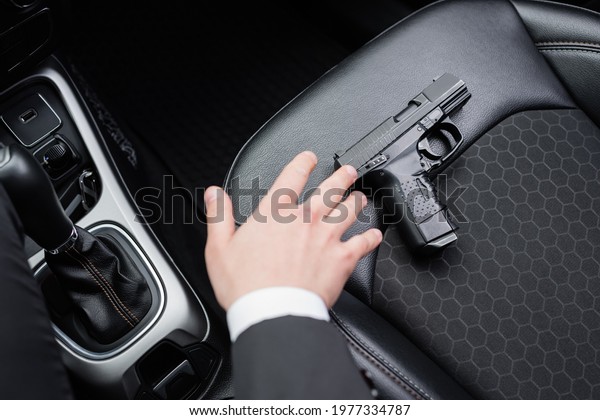top view of bodyguard reaching gun on seat of\
modern automobile