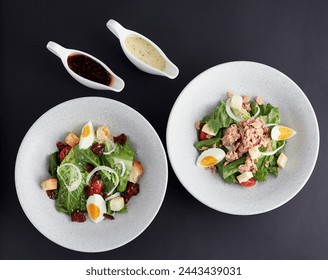 Top view of Boiled egg and tuna with green cos lettuce salad topped with sliced onions, tomato and croutons served in bowl with dipping sauce isolated on black background. Clean food. - Powered by Shutterstock