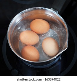 Top View Of Boiling Chicken Eggs In Metal Pot On Electric Stove In Kitchen