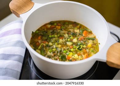 Top View Of Boiling Vegetable Soup Minestrone In White Big Pot On Stove At The Kitchen