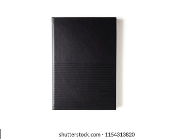 Top View Of Book Or Notebook With Black Leather Cover With Lines Texture Isolated On White Desk Background.