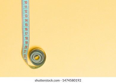 Top view of border frame made of measure tape with empty space for your idea. Sewing and keeping fit concept on orange background.