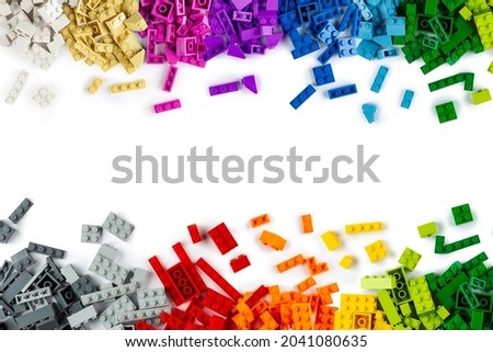 top view of border frame pile various colorful rainbow colored stackable plastic toy bricks isolated on white panorama background.. childhood education construction concept