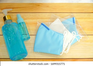 Top View Bottle Of Alcohol Spray, Hand Gel And  Face Mask In Plastic Bag On Wood Table Background. For Anti Bacteria, Virus, Saliva. Protection, Outbreak Concept. Copy Space.