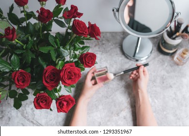 Top View, Bouquet Red Roses, Round Mirror, Female Hands Holds Makeup Brush And Blush On The Marble Vanity Table. Mothers Day Background