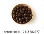 Top View a bowl filled with dark chocolate balls against a clean white background