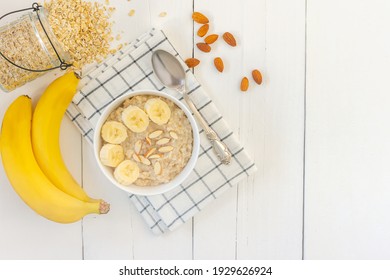 Top view of Bowl of oat flakes with sliced banana close-up on wooden table. - Shutterstock ID 1929626924