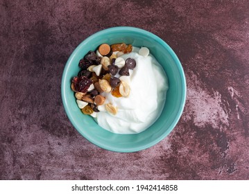 Top View Of A Bowl With Plain Greek Yogurt And A Candy Trail Mix On A Marron Tabletop.