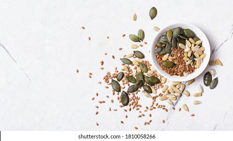 Top view of bowl with pumpkin, sunflower and flax seeds for healthy nutrition on white marble background with copy space - Shutterstock ID 1810058266
