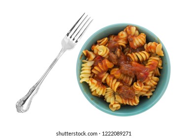 Top View Of A Bowl Of Rotini Pasta In A Sausage And Tomato Sauce With A Fork To The Side Isolated On A White Background.