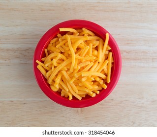 Top View Of A Bowl Of Shredded Sharp Cheddar Cheese On A Wood Table Top Illuminated With Natural Light.