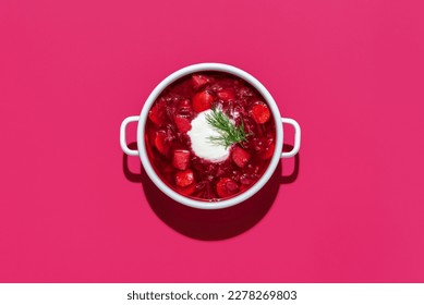 Top view with a bowl of ukrainian borscht with sour cream, isolated on a pink background. Homemade beetroot soup and other vegetables, minimalist on a vibrant colored table. - Powered by Shutterstock