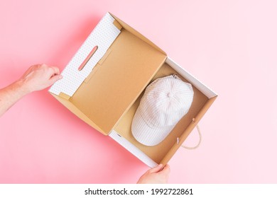 top view of box with cap inside on pink background. concept buying clothes online. electronic commerce. flat lay flat design